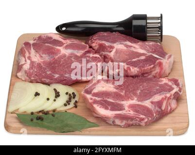 Trois coupes de viande de porc crue avec du poivre noir, de l'oignon et des feuilles de Laurier sur une planche de bois Banque D'Images