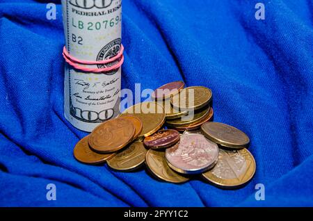 les billets de dollar se sont enroulés dans un tube isolé sur fond bleu. Banque D'Images