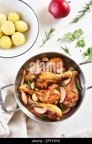 Pilons de poulet cuits avec des pommes et des herbes. Arrière-plan blanc, vue de dessus, plat Banque D'Images