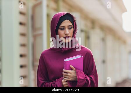 Homme d'affaires arabe confiant souriant et des promenades à Dubaï. Le hijab du sens des affaires arabes est dans les rues contre les gratte-ciels de Dubaï. La femme est dres Banque D'Images