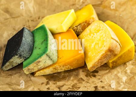 Assortiment de fromages artisanaux de différents types et couleurs sur papier sulfurisé huilé Banque D'Images