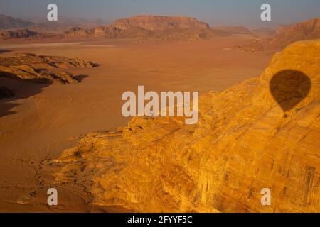 Vue sur le désert de Wadi Rum depuis un ballon d'air chaud au lever du soleil, avec l'ombre de ce ballon vu sur l'une des formations rocheuses, Jordanie, avril 2018 Banque D'Images