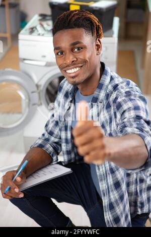 un jeune technicien heureux écrit sur le presse-papiers de la cuisine Banque D'Images