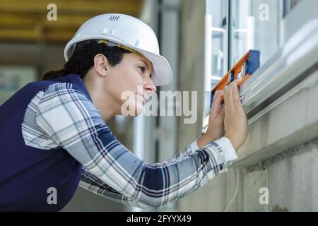 femme utilisant un niveau à bulle sur une fenêtre sil Banque D'Images