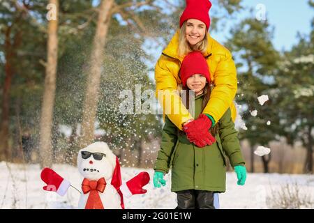 Bonne famille avec bonhomme de neige dans le parc Banque D'Images