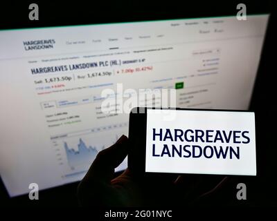 Personne détenant un smartphone avec le logo de la société financière britannique Hargreaves Lansdown plc à l'écran devant le site Web. Mise au point sur l'affichage du téléphone. Banque D'Images