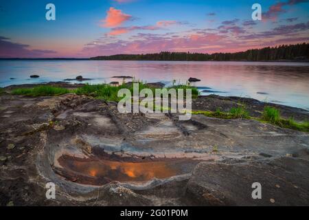 Début de matinée d'été avec un ciel coloré, et des rives rocailleuses et herbeuses à Virebukt dans le lac Vansjø, Østfold, Norvège, Scandinavie. Banque D'Images