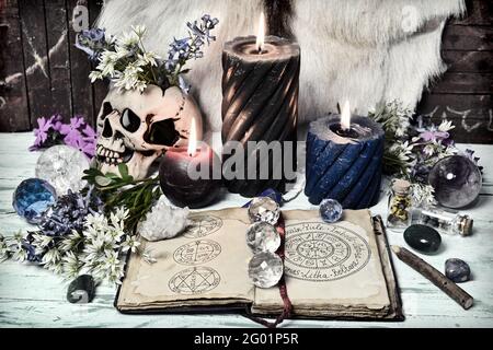 Encore la vie avec un livre ouvert avec des vacances wiccan et des symboles, le cristal et les bougies allumées. Arrière-plan ésotérique, gothique et occulte, Halloween mystique et Banque D'Images
