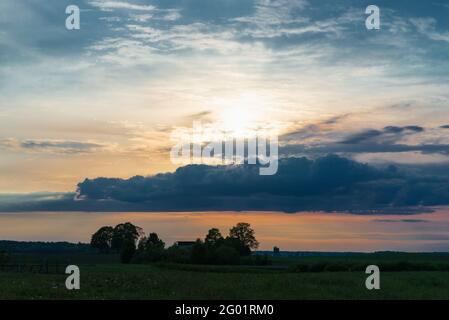 Matin ou soir nuages soleil et champ parmi les arbres dans le temps chaud d'été, belle soirée colorée paysage d'été. Banque D'Images
