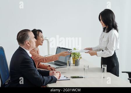 Jeune candidat souriant donnant un curriculum vitae imprimé aux RH directeur général et PDG de l'entreprise avant l'entretien d'embauche Banque D'Images