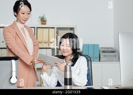 Femme responsable du département qui donne le document à un nouvel employé souriant Banque D'Images
