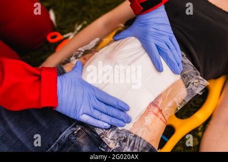 Formation aux premiers soins. Blessures aux jambes. Paramédic en action. Un bandage paramédical une blessure sur l'abdomen d'une femme blessée dans un accident de voiture Banque D'Images