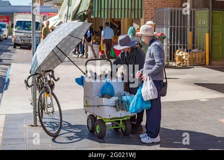 Une ancienne femme vietnamienne australienne achète des légumes dans la rue Dans le Cabramatta de Sydney d'une autre femme illégalement le commerce de rue Banque D'Images