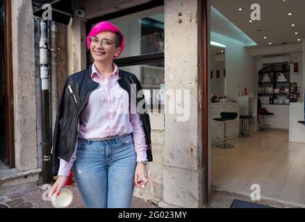 Une jolie dame avec des cheveux roses à l'extérieur d'une boutique qui vend des cosmétiques pour femmes. À Kotor, Monténégro. Banque D'Images