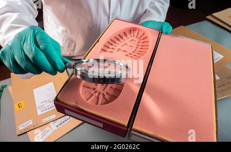 Un scientifique médico-légal étudie des preuves de moisissure de shoeprint dans un laboratoire de crime, image conceptuelle Banque D'Images