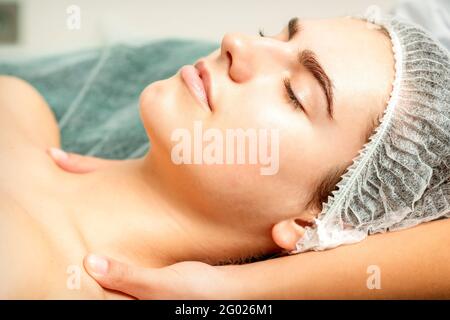 Vue latérale des mains d'une femme thérapeute faisant un massage du cou et des épaules à la jeune femme caucasienne dans le salon de beauté spa Banque D'Images