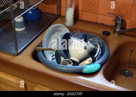 Évier de cuisine débordant de vaisselle sale, bols, assiettes et lave-linge Banque D'Images