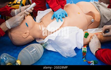 Un paramédical avec des gants en caoutchouc bleu montre comment réanimer le cœur d'une poupée. Exercice de premiers soins Banque D'Images