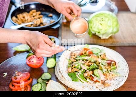 Cuisson rapide des aliments. Mains préparant le tortilla envelopper avec du poulet et de la salade de légumes, kebab gyros remplir. Banque D'Images