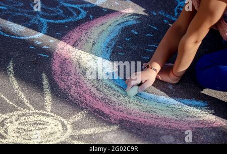 Mignon petit enfant tire le soleil avec la craie dehors, heure d'été, craie. Mise au point sélective. Banque D'Images