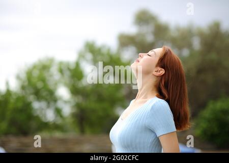 Profil d'une femme heureuse respirant de l'air frais dans un jardin Banque D'Images