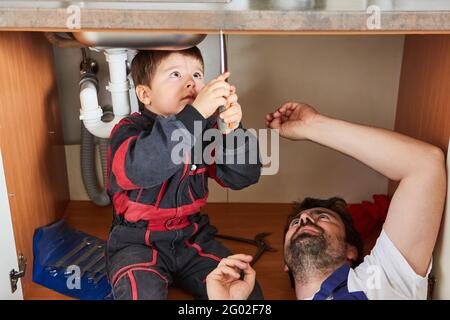 Un enfant de main aide son père à installer ou à réparer un évier Banque D'Images