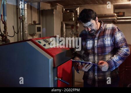 Installateur à côté du chauffage au gaz dans le sous-sol pour l'entretien de la chaudière à condensation Banque D'Images