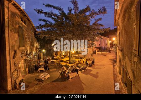 FRANCE - VAUCLUSE - 84 - OPPEDE LE VIEUX : LA PLACE DU VILLAGE ET LA RUE SAINTE CECILE AU CRÉPUSCULE.CETTE BELLE VILLE MÉDIÉVALE EST CONSTRUITE AU SOMMET D'UN OUTC ROCHEUX Banque D'Images