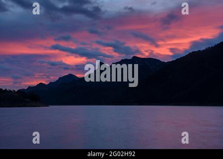 Lever de soleil nuageux au réservoir de Baells. En arrière-plan, la chaîne Serra de Picancel (Berguedà, province de Barcelone, Catalogne, Espagne, Pyrénées) Banque D'Images