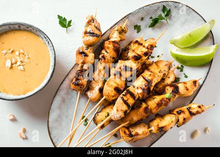 Brochettes de poulet grillé au satay servies avec de la sauce à la chaux et aux arachides, gros plan. Cuisine asiatique de style thaïlandais. Banque D'Images