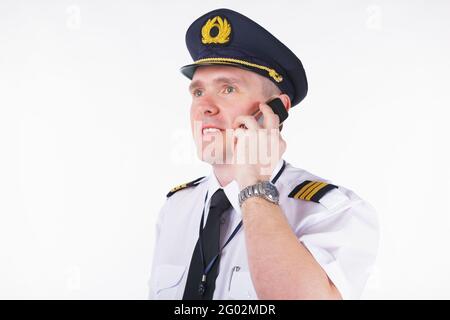 Le pilote de la compagnie aérienne porte une casquette et des épaulets qui parlent sur le téléphone Banque D'Images