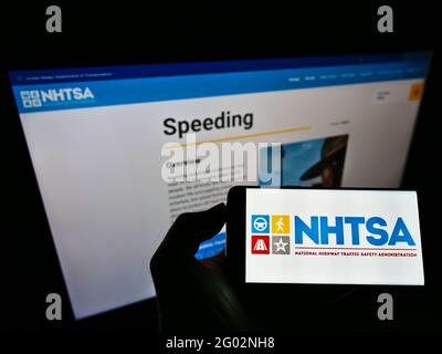 Personne tenant un téléphone mobile avec le logo de la National Highway Traffic Safety Administration (NHTSA) à l'écran avec une page Web. Mise au point sur l'affichage du téléphone. Banque D'Images