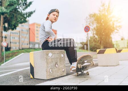 Portrait d'un jeune skateboarder dans une casquette de baseball avec un vieux skateboard dans la rue de la ville. Génération de jeunes passer du temps libre et une population active Banque D'Images