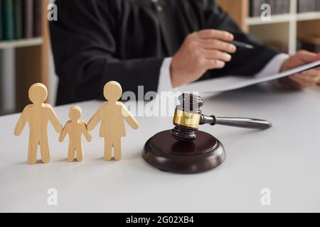 Figurines en bois de famille avec enfant et gavel sur fond de juge menant le processus de divorce. Banque D'Images