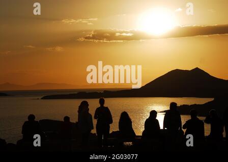 Silhouette panoramique d'un groupe de touristes méconnaissables profitant d'un beau coucher de soleil sur la mer et les sommets de l'île de Cape Sounion, Grèce. Banque D'Images