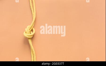 Ficelle jaune nouée sur un arrière-plan de couleur orange Banque D'Images