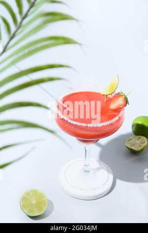 Cocktail fraise Margarita décorer citron vert dans l'ombre ensoleillée sur fond bleu. Orientation verticale. Boisson fraîche d'été. Gros plan. Margarita co Banque D'Images