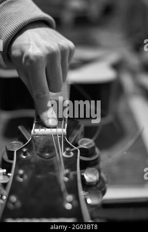 Un agent de service vérifie le son de la guitare pour un réglage plus poussé, une photo en noir et blanc. Banque D'Images