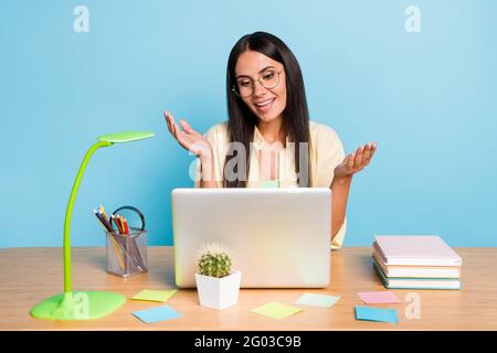 Portrait d'une jolie fille gaie utilisant un ordinateur portable pour assister à une réunion vidéo conférence isolée sur fond bleu vif Banque D'Images