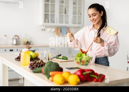 Portrait d'une jeune femme souriante qui prépare une salade fraîche Banque D'Images