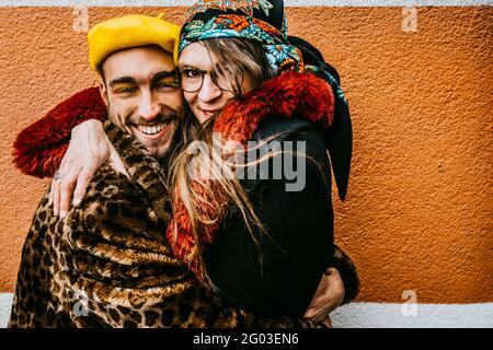 Portrait d'une femme mûre souriante enserrant un ami mâle contre le mur Banque D'Images