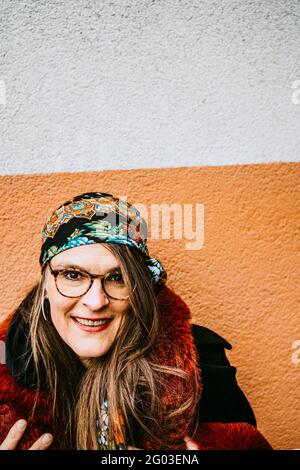 Portrait d'une femme mûre souriante portant un manteau de fourrure contre le mur Banque D'Images