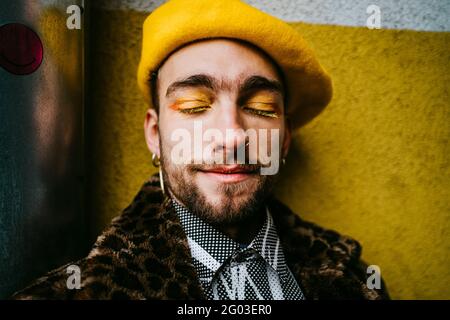 Jeune homme avec les yeux fermés, portant un béret jaune Banque D'Images