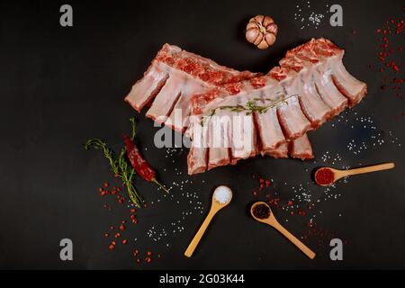 Côtes de porc de porc de filet crues avec assaisonnement sur fond noir. Banque D'Images