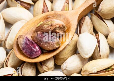 cuillère en bois avec des noix décortiquées sur des pistaches mûres près haut Banque D'Images