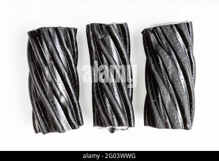 peu de bonbons à la réglisse noire en spirale sur une plaque blanche Banque D'Images