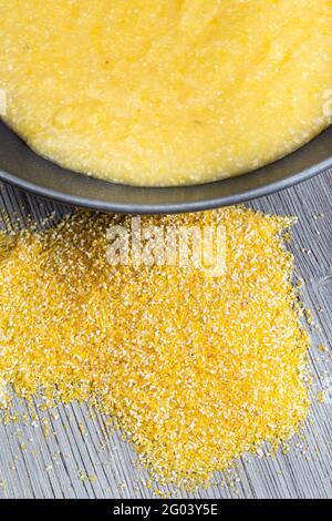 vue de dessus d'une poignée de semoule de maïs et de porridge de maïs cuit dans un bol gris sur une table en bois gris Banque D'Images