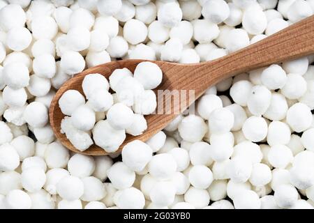 vue de dessus de la cuillère en bois avec perles de tapioca crues à proximité sur la pile de sucre Banque D'Images