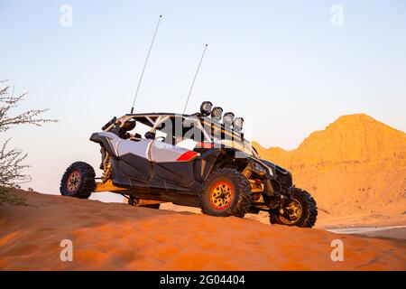 Sharjah, eau, 16.01.2021. Buggy moderne garée sur le sable dans le désert avec montagnes en arrière-plan, Fossil Rock, vue latérale. Banque D'Images