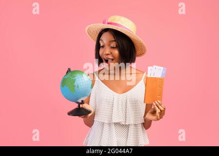 Bonne femme noire, avec globe, passeport et billets d'avion, voyage dans le monde entier, voyage à l'étranger en été Banque D'Images